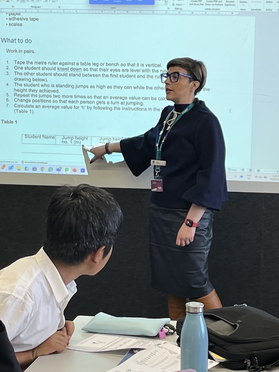 Dr Lucy Cassar in classroom, pointing to text on a projector screen.