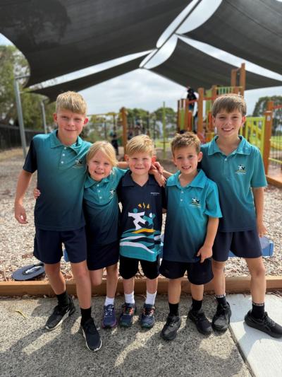 Five Somerville Rise students stand linking arms and smiling in their school playground