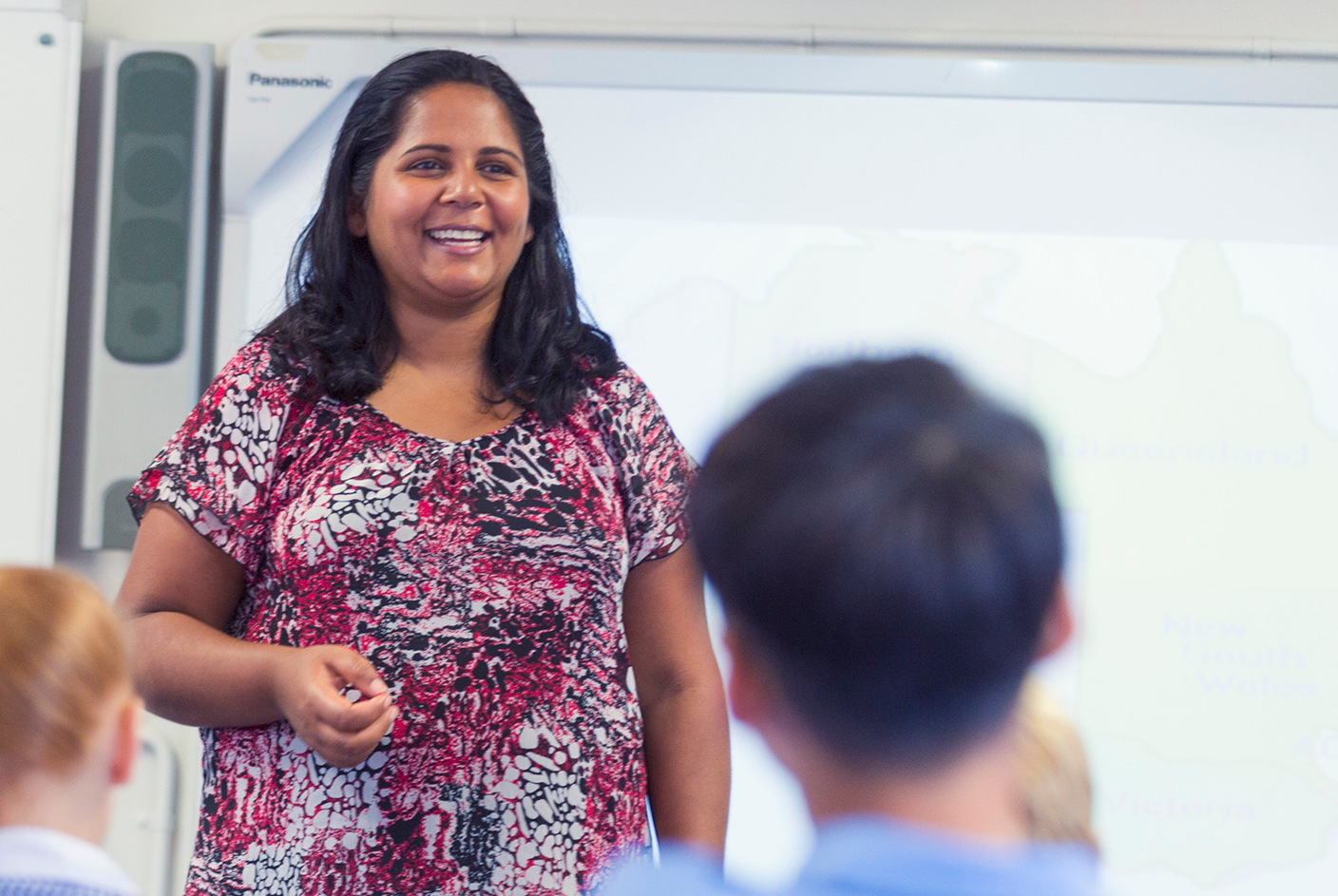 Female teacher smiling in front of class 