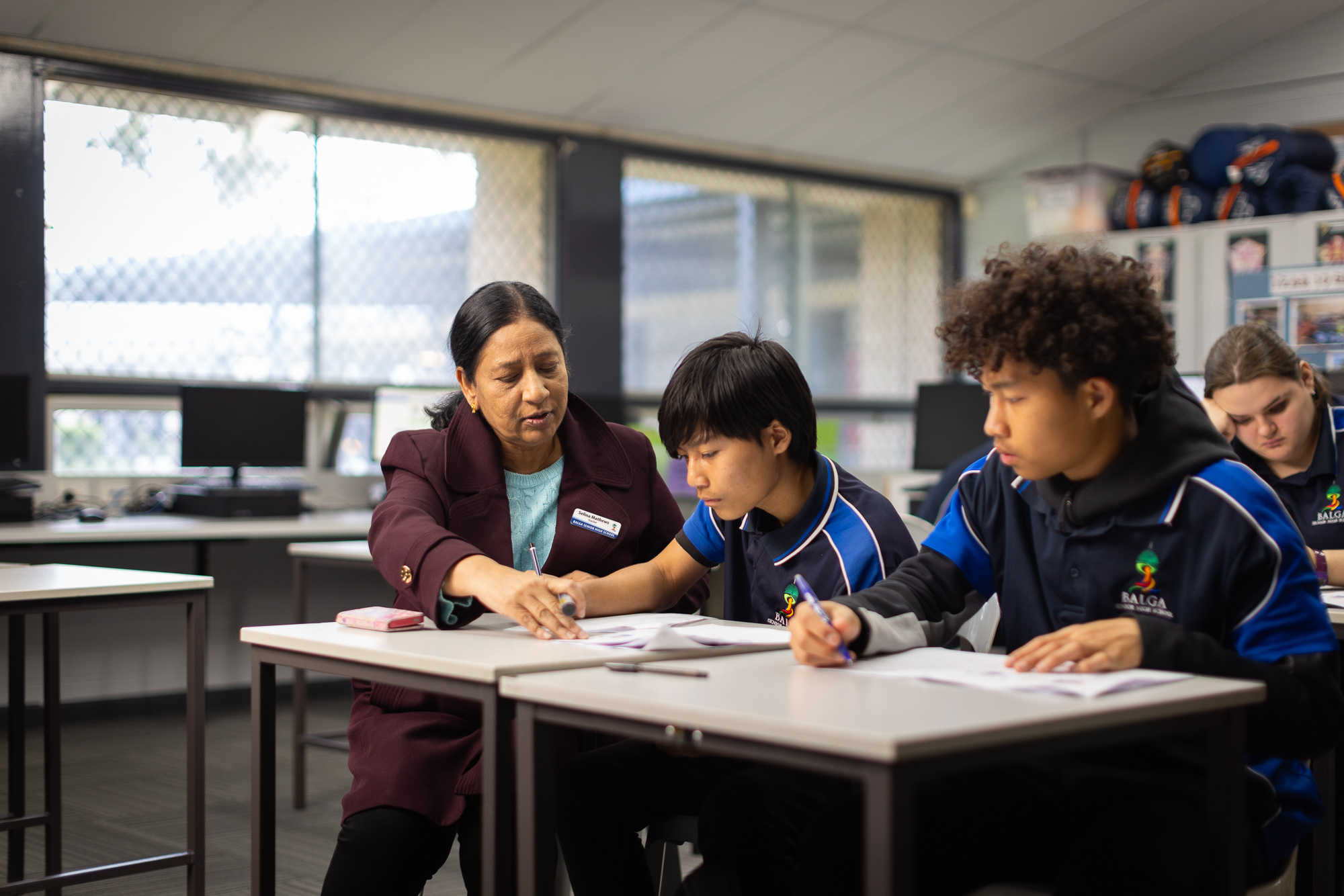 Teacher helping secondary school students with writing.