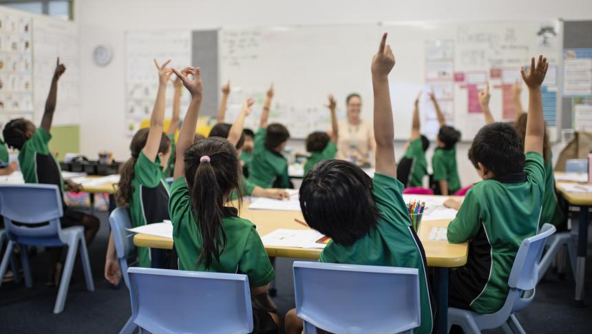 Children with their arms up in a classroom