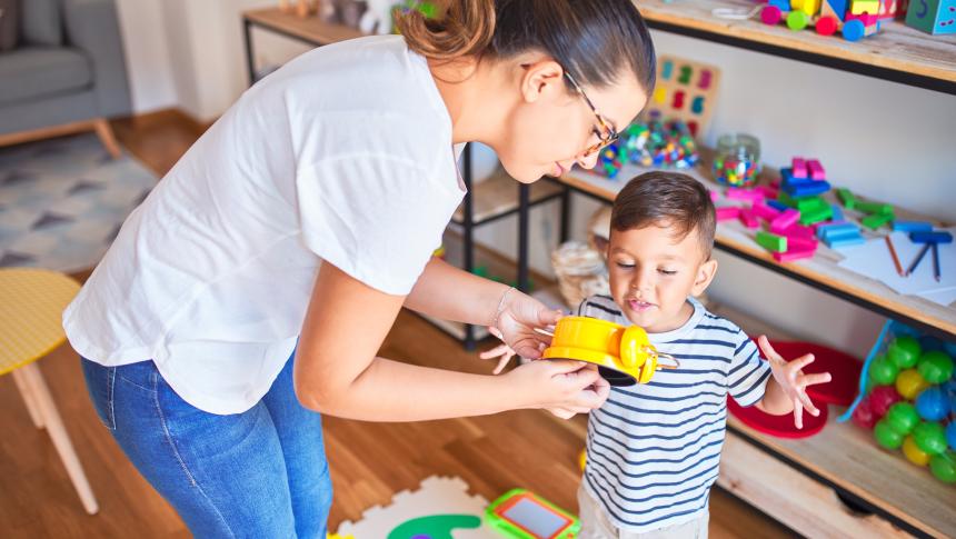 Adult handing a yellow truck to a child