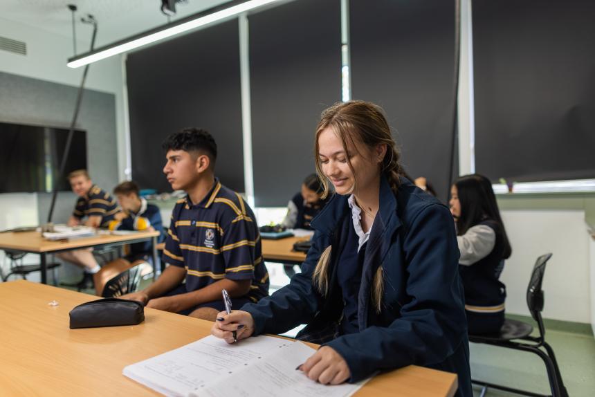 A female student writes in a notebook.