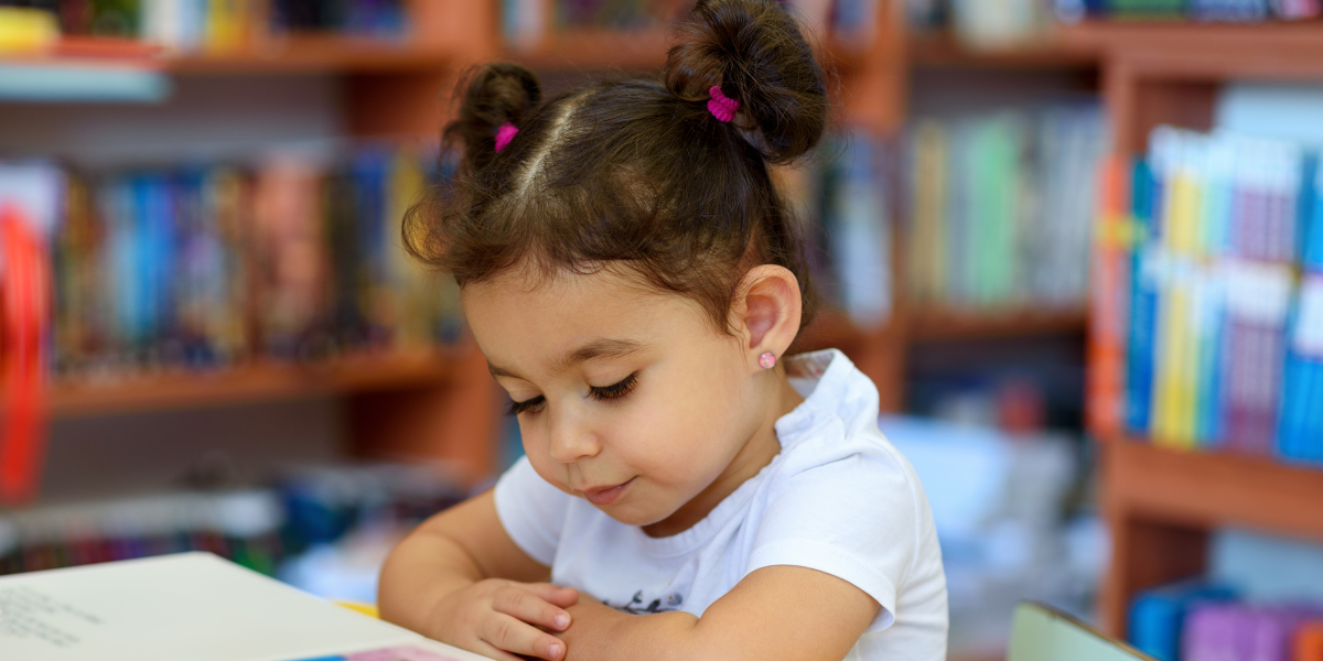 Happy child little girl reading a book